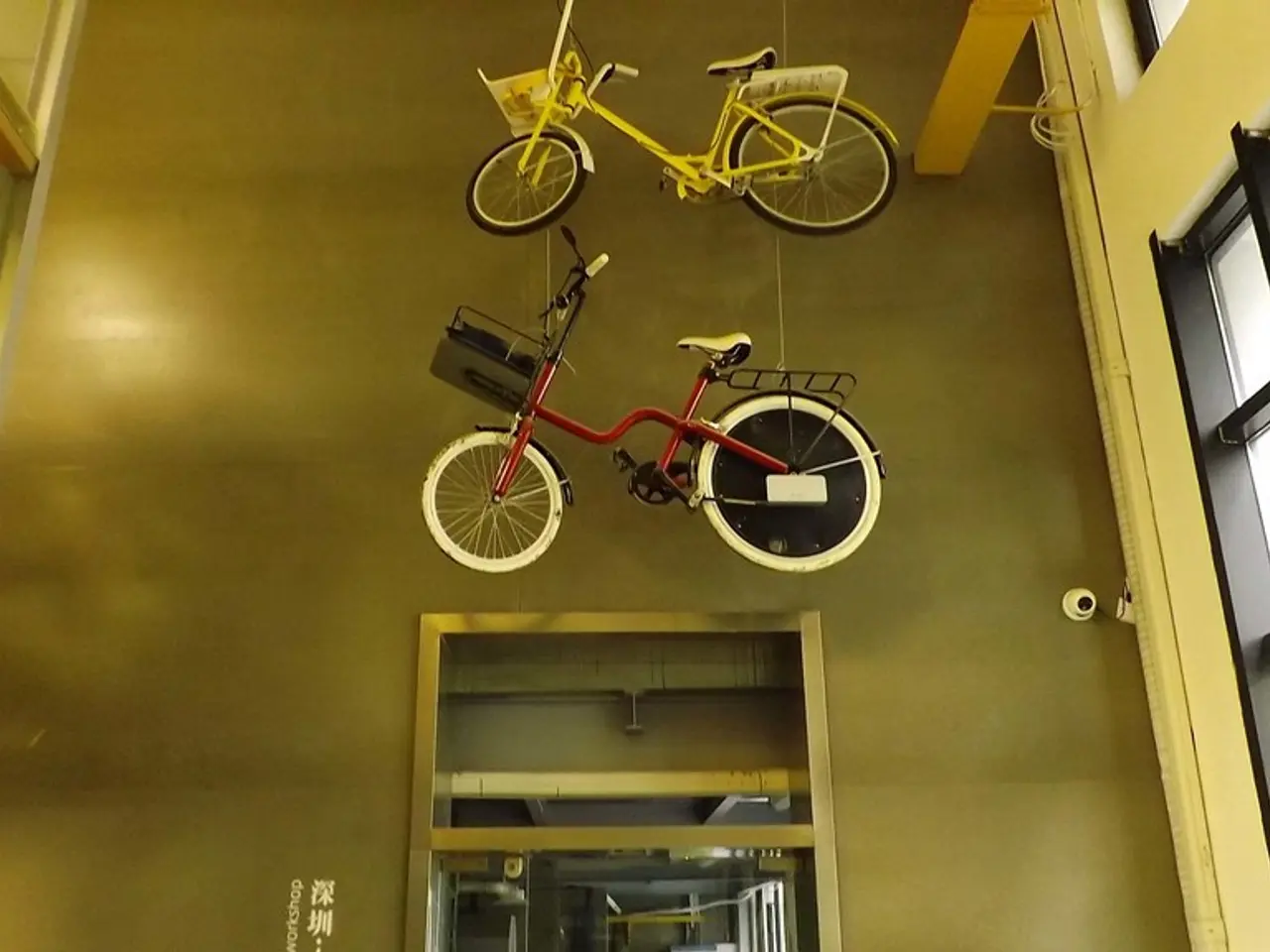 The picture is clicked inside a building. On the top two bicycles are hanged. In the right there is...