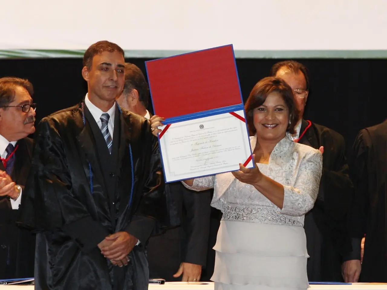 A woman is holding certificate, where men are standing wearing suit.