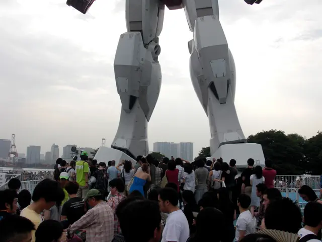 In this image we can see the legs of a robot, in front of that, there are a few people standing and...